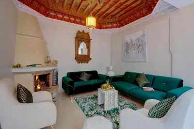 a living room with a green couch and a fireplace at Samira Group & Spa in Marrakech