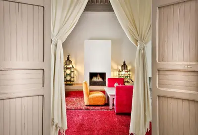 a living room with a fireplace and a red rug at Hotel & Spa Riad Al Jazira in Marrakech