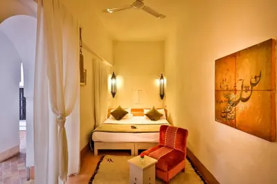a bedroom with a bed and a chair in a room at Hotel & Spa Riad Al Jazira in Marrakech