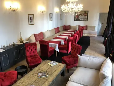 a dining room with a long table and red chairs at Riad 64 Maison D'hôtes & Spa in Marrakech