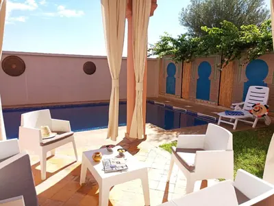 a patio with white chairs and a swimming pool at VILLA ILYANA in Marrakech