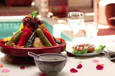 a bowl of vegetables on a table with a glass of wine at Riad Melhoun & Spa in Marrakech