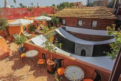 an outdoor patio with tables and chairs and a building at Riad Melhoun & Spa in Marrakech