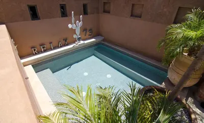 a swimming pool with plants next to a building at Riad Dar 73 in Marrakech