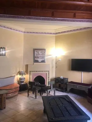 a living room with a fireplace and a tv at la palmeraie village Appartement in Marrakech