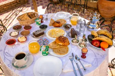 a table topped with plates of breakfast foods and orange juice at Riad Aicha Marrakech in Marrakech