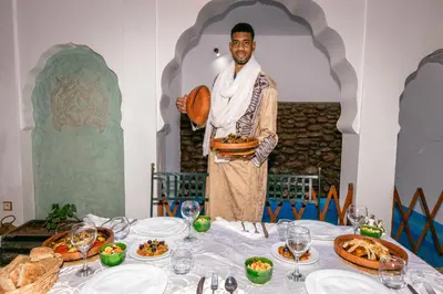 a man holding a plate of food at a table at Riad Aicha Marrakech in Marrakech