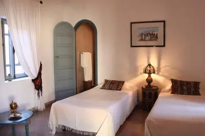 two beds in a room with white walls at Riad Sahara Nour in Marrakech
