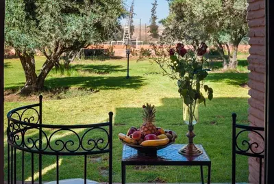a bowl of fruit on a table with two chairs at Charming villa in the heart of Marrakech palm grove in Marrakech