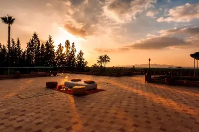 a sunset over a patio with a couch and trees at Charming villa in the heart of Marrakech palm grove in Marrakech