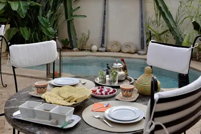 a table with food on it next to a swimming pool at Riad les Ammonites and Spa in Marrakech