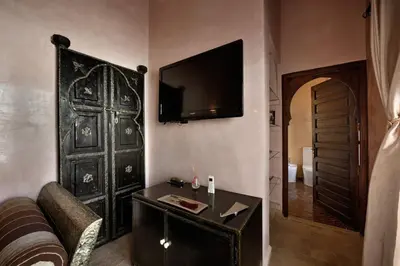 a living room with a couch and a television on a wall at Riad les Ammonites and Spa in Marrakech