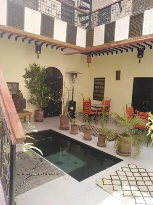a patio with a swimming pool with potted plants at Riad JEREMY in Marrakech