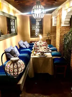 a dining room with a long table with blue couches at RIAD DES DEUX MERS in Marrakech