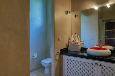 a bathroom with a sink and a toilet and a mirror at Villas 95 Appart'Hôtel in Marrakech
