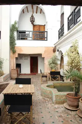 a courtyard of a building with a table and a fountain at Riad Spa Dar Nimbus in Marrakech