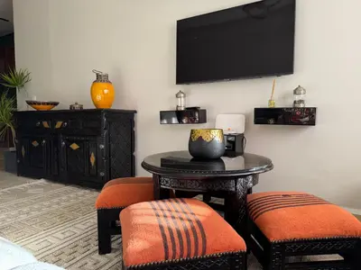 a living room with a table and chairs and a tv at Caprice Palace in Marrakech