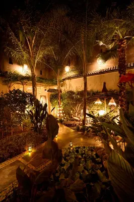 a woman sitting on a bench in a garden at night at Riad Dar Amanza en exclusivité avec 4 chambres au coeur de la médina in Marrakech