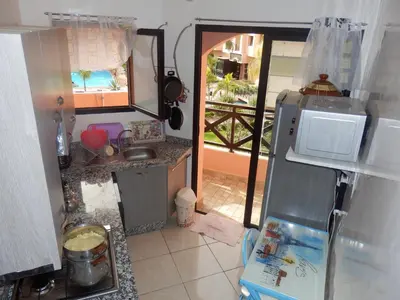 a small kitchen with a sink and a refrigerator at Appart Piscine Jardin somptueux à 2 min de palmeraie et 10 min de Majorelle in Marrakech