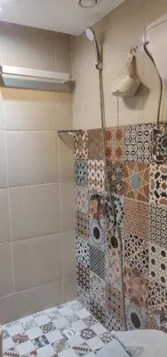 a shower in a bathroom with tiles on the wall at Appart Piscine Jardin somptueux à 2 min de palmeraie et 10 min de Majorelle in Marrakech