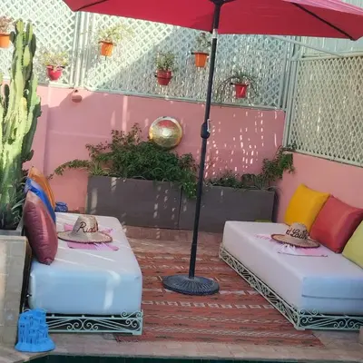 two beds sitting under an umbrella on a patio at Riad Laith in Marrakech