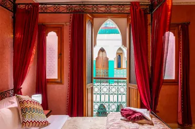 a bedroom with a bed with red curtains and a window at Riad Bianca Marrakech in Marrakech