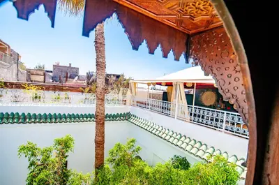 a view of a swimming pool with a palm tree at Hotel & Spa Riad Dar El Aila in Marrakech