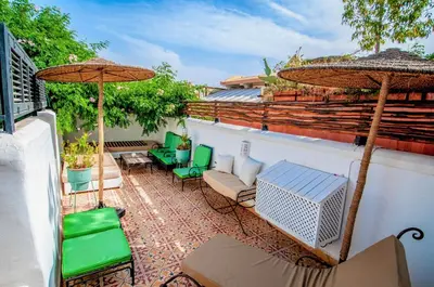 a patio with chairs and umbrellas on a roof at Hotel & Spa Riad Dar El Aila in Marrakech