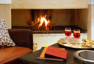 a table with two glasses of wine in front of a fireplace at Riad Dar Housnia in Marrakech