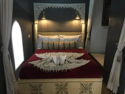 a bedroom with a bed with a red comforter at Riad Blue Berber in Marrakech