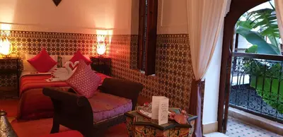 a living room with a bed and a chair and a window at Riad Mehdia & spa in Marrakech