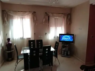 a living room with a dining table and a television at LINA APPARTEMENT in Marrakech
