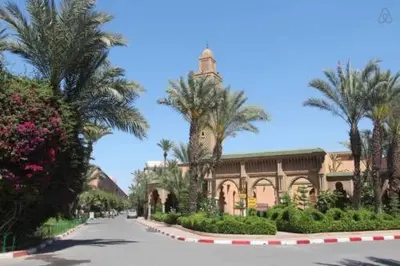 a building on a street with palm trees and a road at Riad Safae in Marrakech