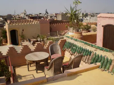 a patio with chairs and a table on a roof at Riad Ifoulki in Marrakech