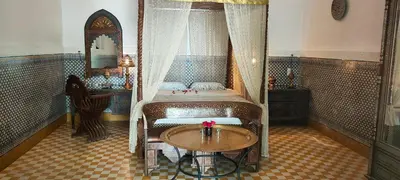 a bedroom with a bed with a table and a mirror at Riad Ifoulki in Marrakech