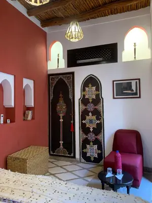 a room with a bed and a chair and a table at Riad Boussa in Marrakech