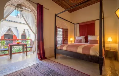 a bedroom with a canopy bed and a balcony at Riad Dar Karma in Marrakech