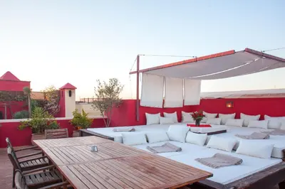 a patio with a wooden table and white couches at Riad Dar Karma in Marrakech