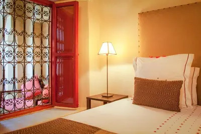a bedroom with a bed and a lamp and a window at Riad Dar Karma in Marrakech