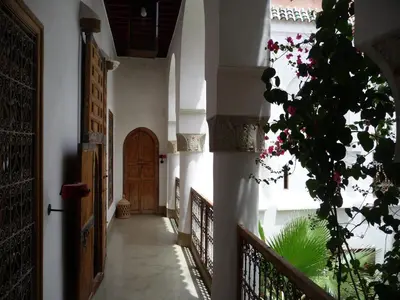 a hallway of a building with a door and flowers at Riad Matham in Marrakech