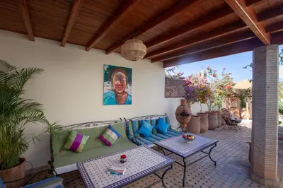 a patio with a couch and tables and a painting at Dar Halima in Marrakech