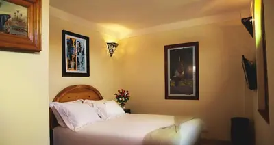 a bedroom with a white bed and two pictures on the wall at Riad Granvilier in Marrakech
