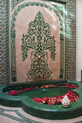 a fountain with flowers in front of a wall at Riad Granvilier in Marrakech
