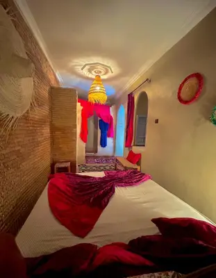 a bedroom with a large bed with red sheets at Riad Alamine in Marrakech
