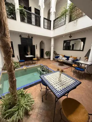 an indoor courtyard with a pool and tables and chairs at Dar Fangui in Marrakech