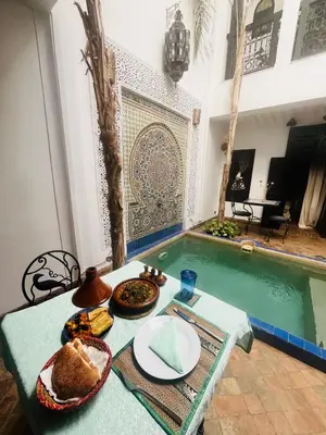 a table with a plate of food next to a swimming pool at Dar Fangui in Marrakech