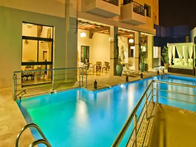 a swimming pool with blue water in a building at Hotel Lawrence d'Arabie in Marrakech