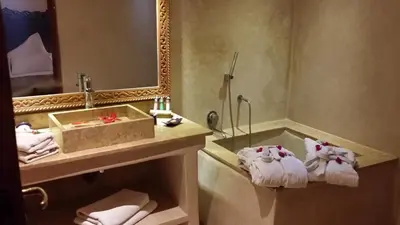 a bathroom with a sink and a tub with towels at Riad Al Ksar & Spa in Marrakech