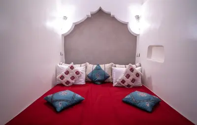 a room with a red bed with pillows on it at Riad Hotel Sherazade in Marrakech