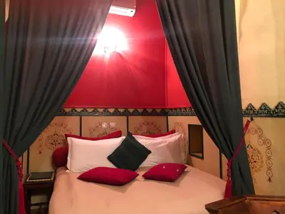 a bedroom with a bed with red and white pillows at Riad Hotel Sherazade in Marrakech